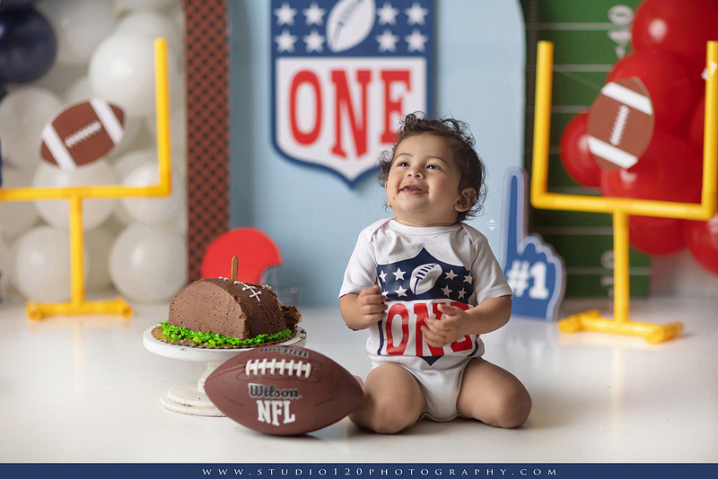“Studio 120 Photography first birthday football cake smash session featuring a custom football set, milestone portraits, and smash cake celebration.”