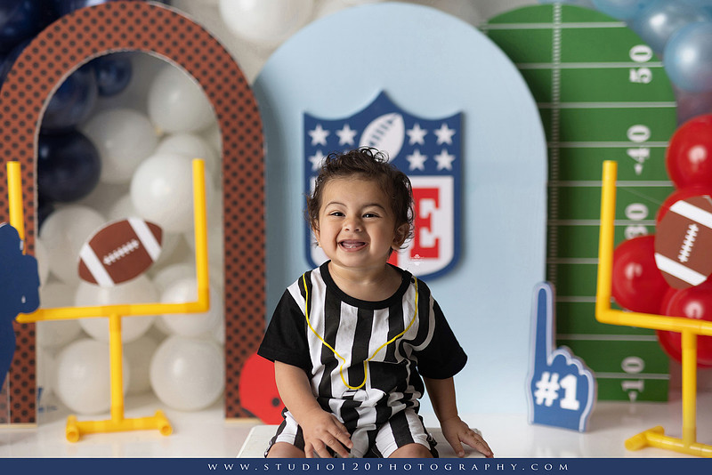 “Studio 120 Photography first birthday football cake smash session featuring a custom football set, milestone portraits, and smash cake celebration.”