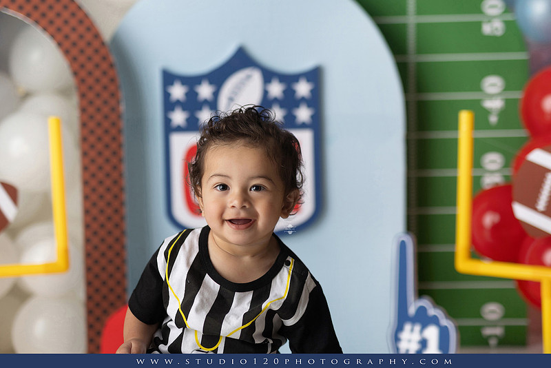 “Studio 120 Photography first birthday football cake smash session featuring a custom football set, milestone portraits, and smash cake celebration.”
