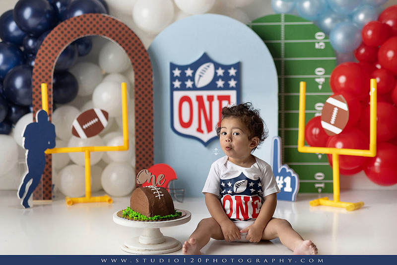 “Studio 120 Photography first birthday football cake smash session featuring a custom football set, milestone portraits, and smash cake celebration.”