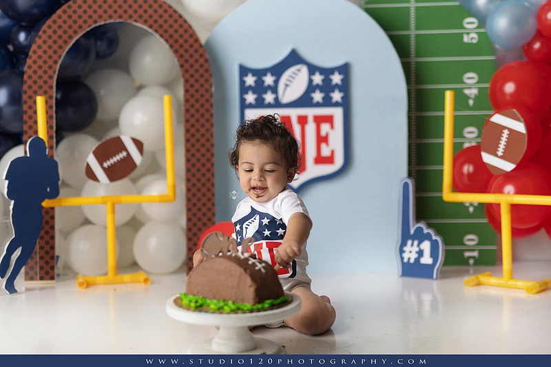 “Studio 120 Photography first birthday football cake smash session featuring a custom football set, milestone portraits, and smash cake celebration.”
