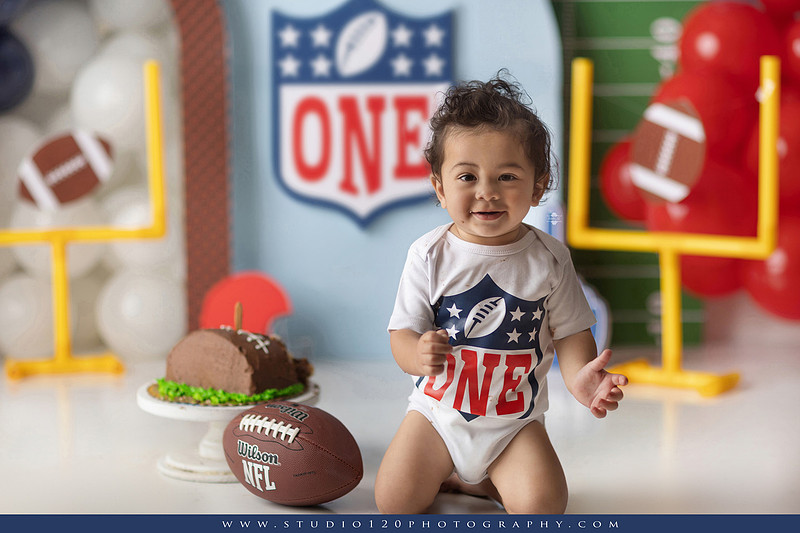 “Studio 120 Photography first birthday football cake smash session featuring a custom football set, milestone portraits, and smash cake celebration.”