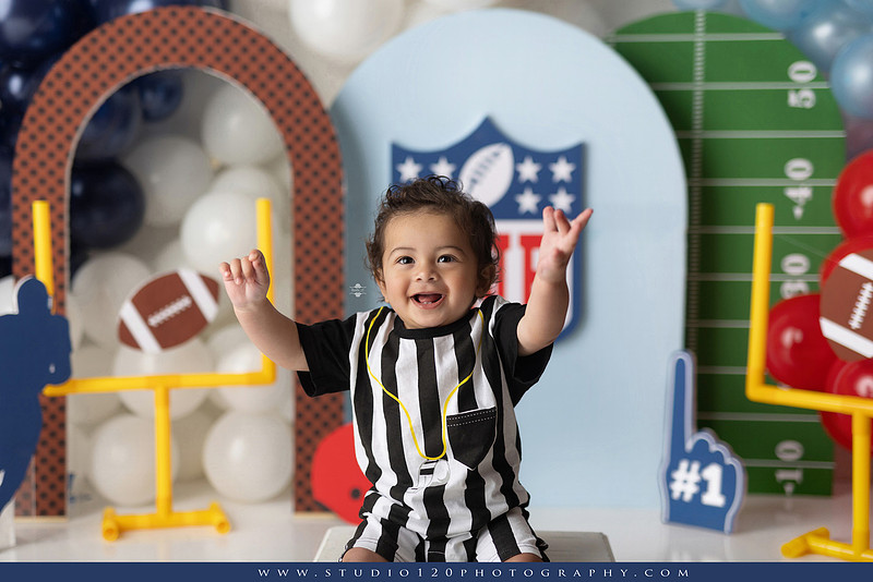 “Studio 120 Photography first birthday football cake smash session featuring a custom football set, milestone portraits, and smash cake celebration.”