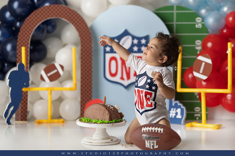 “Studio 120 Photography first birthday football cake smash session featuring a custom football set, milestone portraits, and smash cake celebration.”