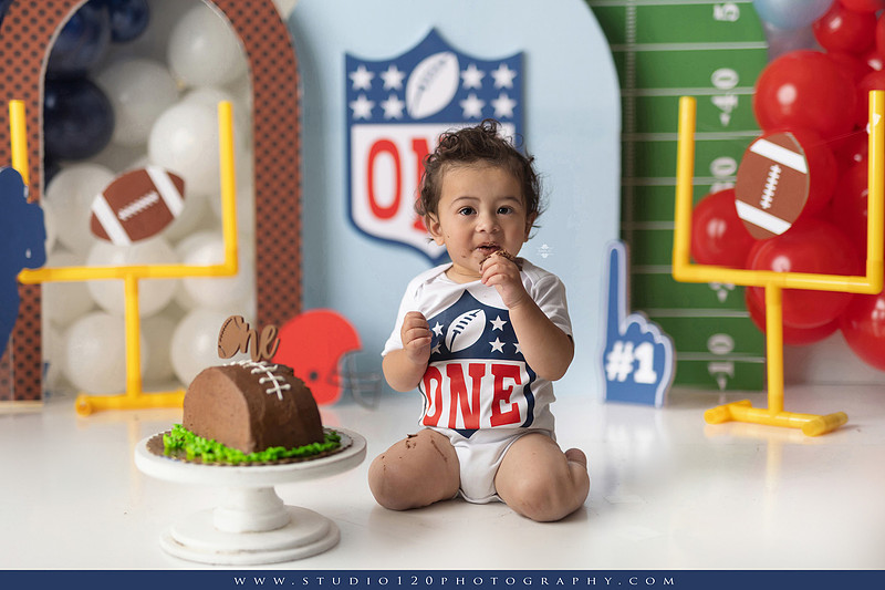 “Studio 120 Photography first birthday football cake smash session featuring a custom football set, milestone portraits, and smash cake celebration.”