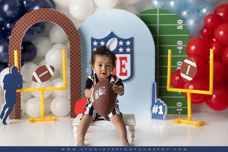 “Studio 120 Photography first birthday football cake smash session featuring a custom football set, milestone portraits, and smash cake celebration.”