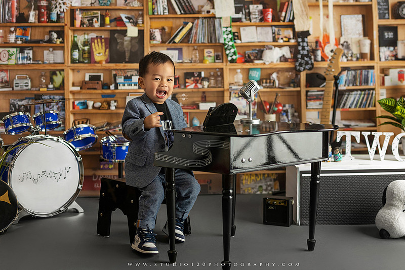 Two-year-old musician themed photo session inspired by NPR Tiny Desk, featuring a toddler holding an electric guitar in a studio music setting