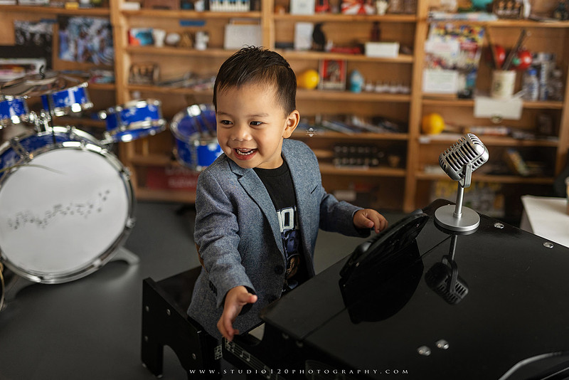 Two-year-old musician themed photo session inspired by NPR Tiny Desk, featuring a toddler holding an electric guitar in a studio music setting
