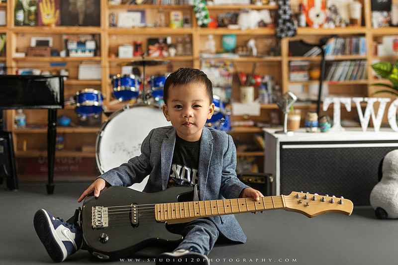 Two-year-old musician themed photo session inspired by NPR Tiny Desk, featuring a toddler holding an electric guitar in a studio music setting