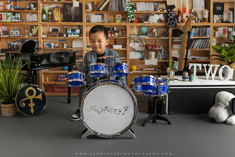 Two-year-old musician themed photo session inspired by NPR Tiny Desk, featuring a toddler holding an electric guitar in a studio music setting