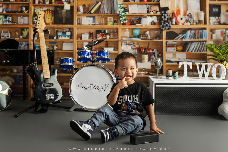 Two-year-old musician themed photo session inspired by NPR Tiny Desk, featuring a toddler holding an electric guitar in a studio music setting