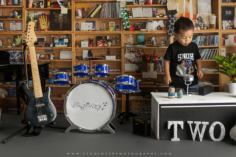 Two-year-old musician themed photo session inspired by NPR Tiny Desk, featuring a toddler holding an electric guitar in a studio music setting