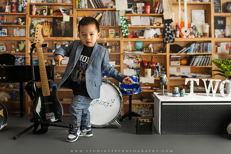 Two-year-old musician themed photo session inspired by NPR Tiny Desk, featuring a toddler holding an electric guitar in a studio music setting