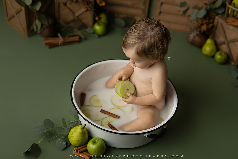 EvotoOne-year-old baby wearing a cowboy hat sits on a rustic honky-tonk stage with vintage posters, string lights, and a neon “One Night Only” sign during a country-themed milestone photo session.