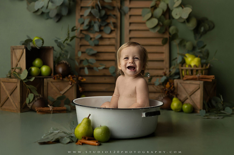EvotoOne-year-old baby wearing a cowboy hat sits on a rustic honky-tonk stage with vintage posters, string lights, and a neon “One Night Only” sign during a country-themed milestone photo session.