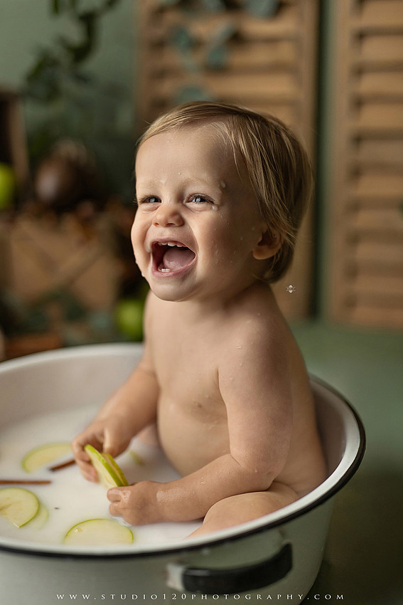 EvotoOne-year-old baby wearing a cowboy hat sits on a rustic honky-tonk stage with vintage posters, string lights, and a neon “One Night Only” sign during a country-themed milestone photo session.