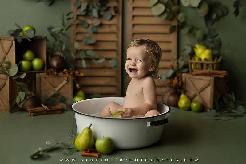 EvotoOne-year-old baby wearing a cowboy hat sits on a rustic honky-tonk stage with vintage posters, string lights, and a neon “One Night Only” sign during a country-themed milestone photo session.