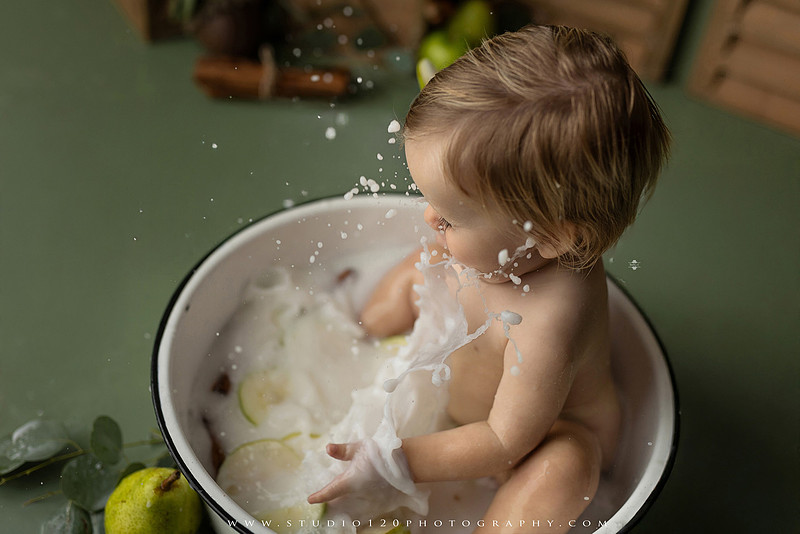 EvotoOne-year-old baby wearing a cowboy hat sits on a rustic honky-tonk stage with vintage posters, string lights, and a neon “One Night Only” sign during a country-themed milestone photo session.