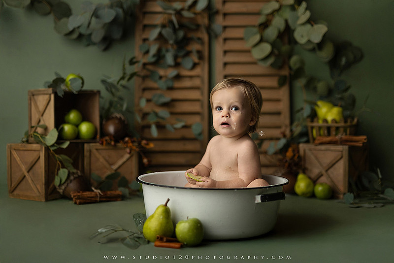 EvotoOne-year-old baby wearing a cowboy hat sits on a rustic honky-tonk stage with vintage posters, string lights, and a neon “One Night Only” sign during a country-themed milestone photo session.