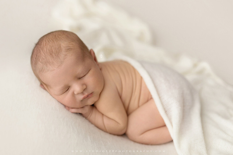 Custom newborn photography session in Ramona, California featuring a baby posed in cozy neutral tones with safari-inspired scenes, teddy bears, and a playful business suit setup, created using studio styling and digital backdrops by a San Diego newborn photographer.