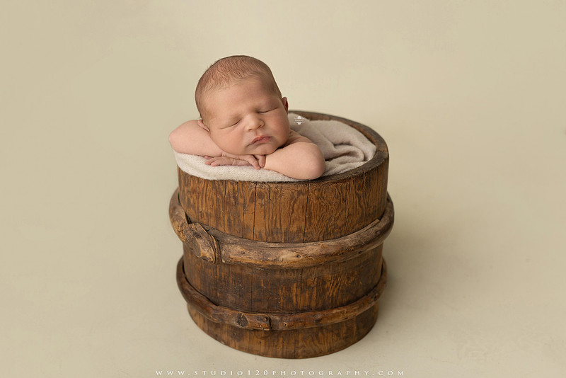 Custom newborn photography session in Ramona, California featuring a baby posed in cozy neutral tones with safari-inspired scenes, teddy bears, and a playful business suit setup, created using studio styling and digital backdrops by a San Diego newborn photographer.