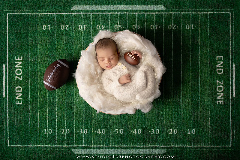 “newborn baby football themed photo with mini football and green turf backdrop”
“adorable infant posed with football props celebrating Super Bowl 2026 newborn session”
“sports baby photography football style end zone setup newborn portrait”