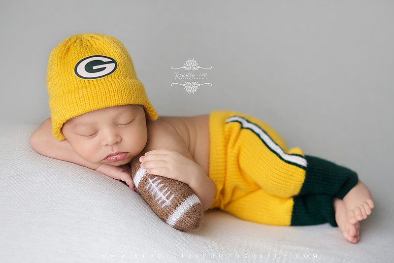 “newborn baby football themed photo with mini football and green turf backdrop”
“adorable infant posed with football props celebrating Super Bowl 2026 newborn session”
“sports baby photography football style end zone setup newborn portrait”