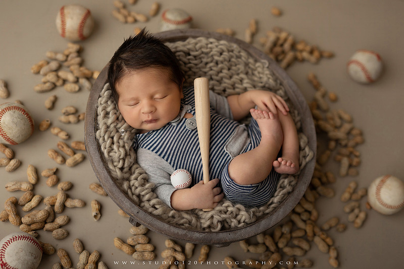 “newborn baby baseball photo with miniature bat and glove props”
“baseball themed newborn photography with baby and ball rustic sports setup”
“infant portrait styled with baseball, glove, and classic sports memorabilia”