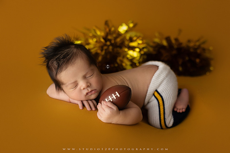 “newborn baby football themed photo with mini football and green turf backdrop”
“adorable infant posed with football props celebrating Super Bowl 2026 newborn session”
“sports baby photography football style end zone setup newborn portrait”
