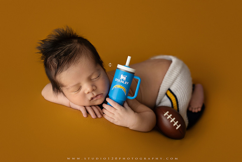 “newborn baby football themed photo with mini football and green turf backdrop”
“adorable infant posed with football props celebrating Super Bowl 2026 newborn session”
“sports baby photography football style end zone setup newborn portrait”