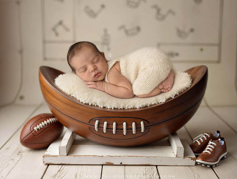 “newborn baby football themed photo with mini football and green turf backdrop”
“adorable infant posed with football props celebrating Super Bowl 2026 newborn session”
“sports baby photography football style end zone setup newborn portrait”