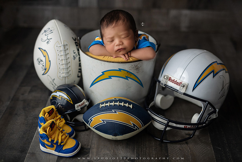 “newborn baby football themed photo with mini football and green turf backdrop”
“adorable infant posed with football props celebrating Super Bowl 2026 newborn session”
“sports baby photography football style end zone setup newborn portrait”