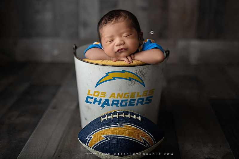 “newborn baby football themed photo with mini football and green turf backdrop”
“adorable infant posed with football props celebrating Super Bowl 2026 newborn session”
“sports baby photography football style end zone setup newborn portrait”