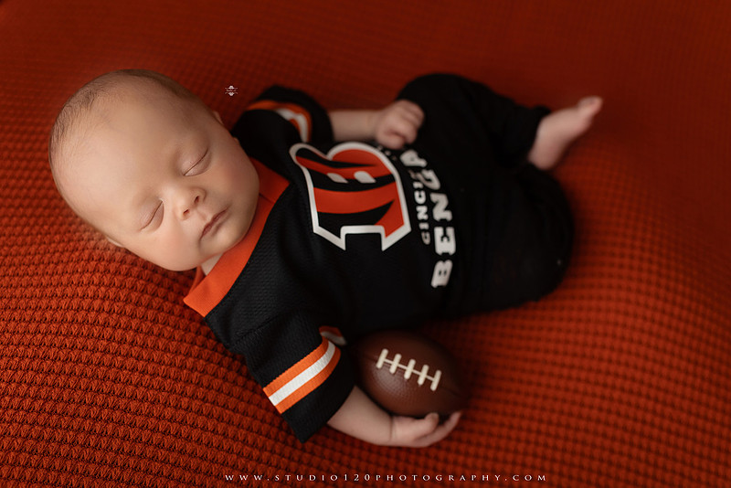 “newborn baby football themed photo with mini football and green turf backdrop”
“adorable infant posed with football props celebrating Super Bowl 2026 newborn session”
“sports baby photography football style end zone setup newborn portrait”