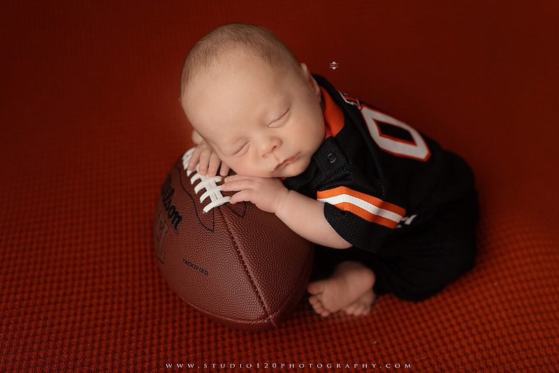 “newborn baby football themed photo with mini football and green turf backdrop”
“adorable infant posed with football props celebrating Super Bowl 2026 newborn session”
“sports baby photography football style end zone setup newborn portrait”