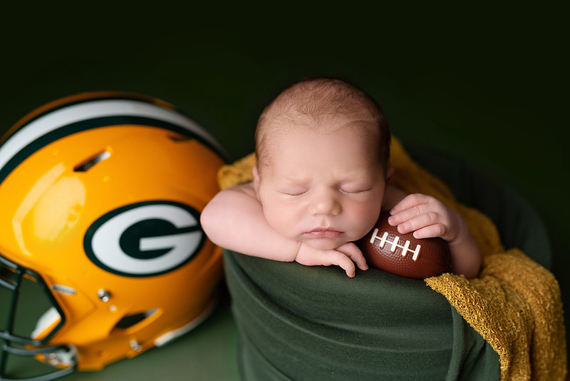“newborn baby football themed photo with mini football and green turf backdrop”
“adorable infant posed with football props celebrating Super Bowl 2026 newborn session”
“sports baby photography football style end zone setup newborn portrait”