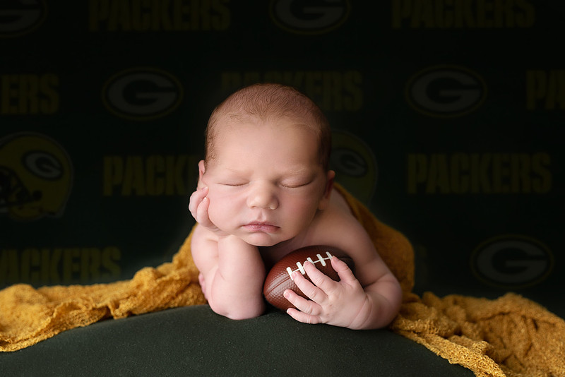 “newborn baby football themed photo with mini football and green turf backdrop”
“adorable infant posed with football props celebrating Super Bowl 2026 newborn session”
“sports baby photography football style end zone setup newborn portrait”