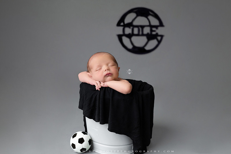 “newborn baby soccer themed photo holding black and white soccer ball”
“soccer sports newborn portrait with baby curled around soccer ball”
“infant soccer photography session with classic soccer ball and soft wrap”