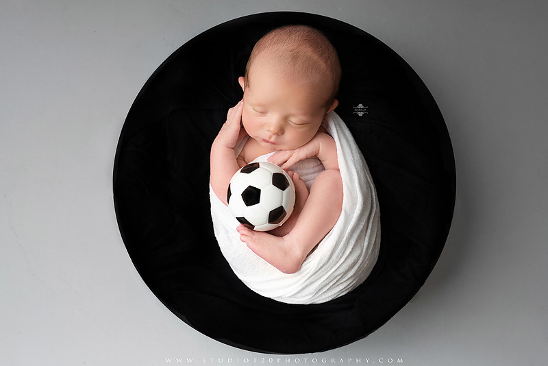 “newborn baby soccer themed photo holding black and white soccer ball”
“soccer sports newborn portrait with baby curled around soccer ball”
“infant soccer photography session with classic soccer ball and soft wrap”