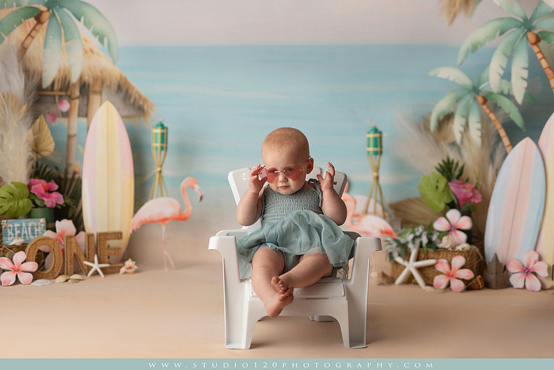 “first birthday portrait of baby in white dress with floral accents in light and airy studio”
“elegant first birthday portrait session with baby in white dress and neutral backdrop”
“luxe coastal cake smash with beach themed backdrop, flamingos and tropical decor”
“baby girl beach themed cake smash with pastel cake and tropical surfboard props”
“coastal first birthday cake smash with flamingo accents and soft beach colors”
“tropical cake smash photography featuring baby and pastel beach themed set”
“baby enjoying cake smash in coastal themed studio with palm trees and flamingos”
“beach inspired cake smash session with baby standing in cake and tropical decor”
“luxury cake smash photography with coastal beach theme and soft pastel tones”