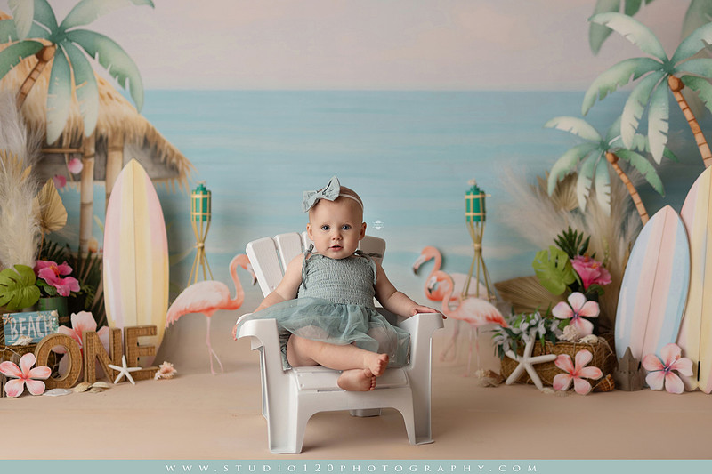 “first birthday portrait of baby in white dress with floral accents in light and airy studio”
“elegant first birthday portrait session with baby in white dress and neutral backdrop”
“luxe coastal cake smash with beach themed backdrop, flamingos and tropical decor”
“baby girl beach themed cake smash with pastel cake and tropical surfboard props”
“coastal first birthday cake smash with flamingo accents and soft beach colors”
“tropical cake smash photography featuring baby and pastel beach themed set”
“baby enjoying cake smash in coastal themed studio with palm trees and flamingos”
“beach inspired cake smash session with baby standing in cake and tropical decor”
“luxury cake smash photography with coastal beach theme and soft pastel tones”