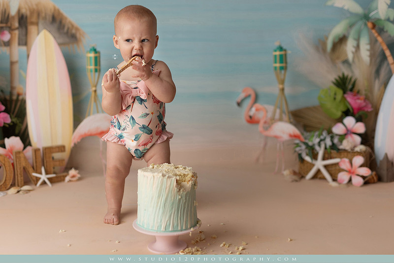 “first birthday portrait of baby in white dress with floral accents in light and airy studio”
“elegant first birthday portrait session with baby in white dress and neutral backdrop”
“luxe coastal cake smash with beach themed backdrop, flamingos and tropical decor”
“baby girl beach themed cake smash with pastel cake and tropical surfboard props”
“coastal first birthday cake smash with flamingo accents and soft beach colors”
“tropical cake smash photography featuring baby and pastel beach themed set”
“baby enjoying cake smash in coastal themed studio with palm trees and flamingos”
“beach inspired cake smash session with baby standing in cake and tropical decor”
“luxury cake smash photography with coastal beach theme and soft pastel tones”