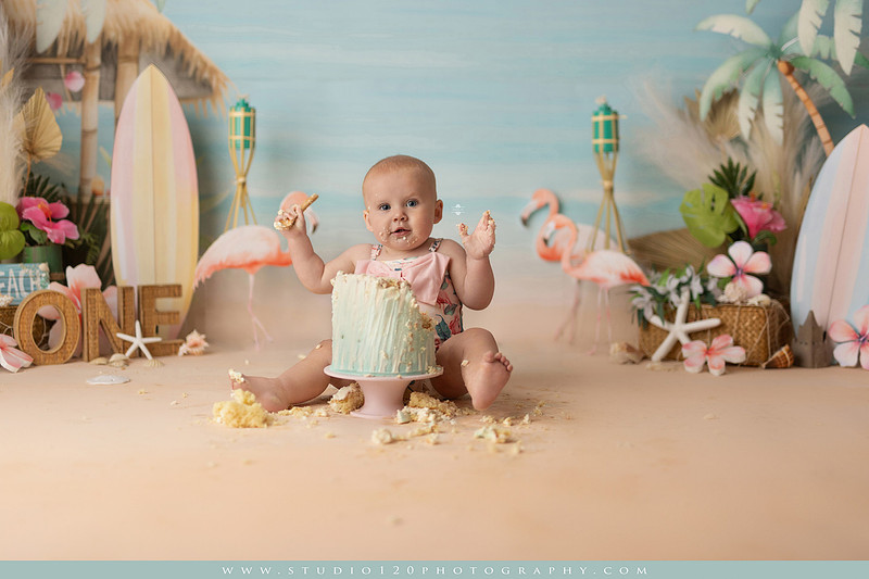 “first birthday portrait of baby in white dress with floral accents in light and airy studio”
“elegant first birthday portrait session with baby in white dress and neutral backdrop”
“luxe coastal cake smash with beach themed backdrop, flamingos and tropical decor”
“baby girl beach themed cake smash with pastel cake and tropical surfboard props”
“coastal first birthday cake smash with flamingo accents and soft beach colors”
“tropical cake smash photography featuring baby and pastel beach themed set”
“baby enjoying cake smash in coastal themed studio with palm trees and flamingos”
“beach inspired cake smash session with baby standing in cake and tropical decor”
“luxury cake smash photography with coastal beach theme and soft pastel tones”