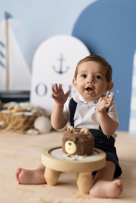 Boy's first birthday Ralph Lauren nautical cake smash session in San Diego featuring sailboats, teddy bears, and blue nautical décor.