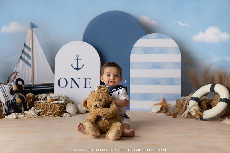 Boy's first birthday Ralph Lauren nautical cake smash session in San Diego featuring sailboats, teddy bears, and blue nautical décor.