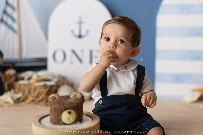 Boy's first birthday Ralph Lauren nautical cake smash session in San Diego featuring sailboats, teddy bears, and blue nautical décor.