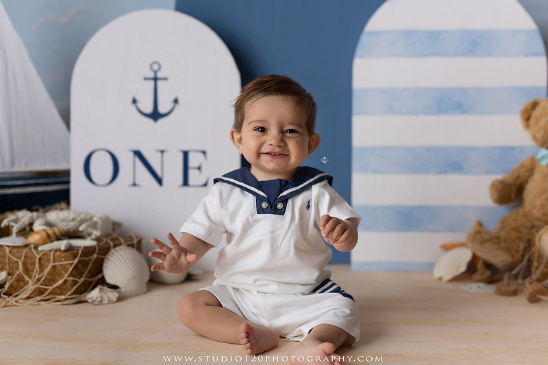 Boy's first birthday Ralph Lauren nautical cake smash session in San Diego featuring sailboats, teddy bears, and blue nautical décor.