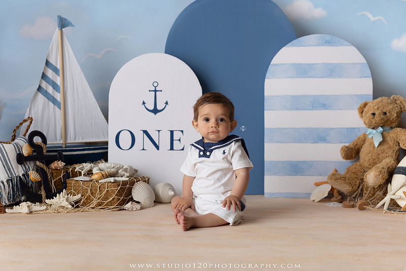 Boy's first birthday Ralph Lauren nautical cake smash session in San Diego featuring sailboats, teddy bears, and blue nautical décor.