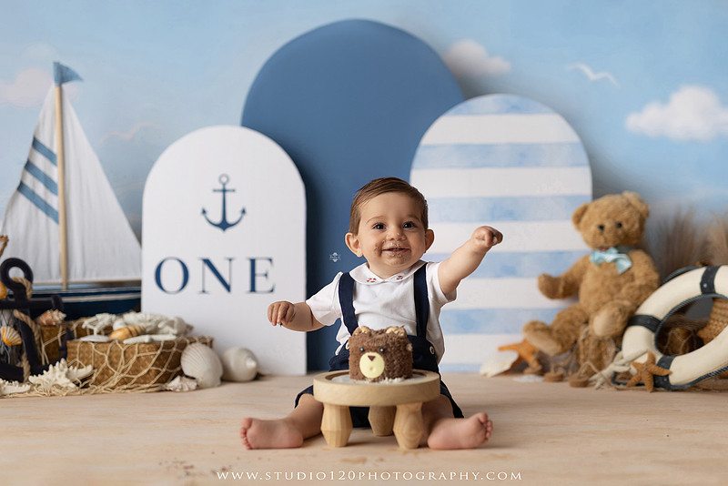 Boy's first birthday Ralph Lauren nautical cake smash session in San Diego featuring sailboats, teddy bears, and blue nautical décor.