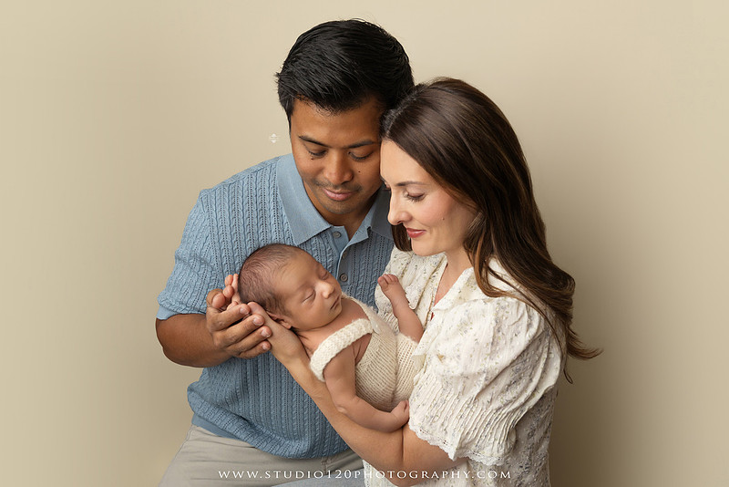 Parents cuddling their newborn baby boy during a family portrait session at Studio 120 Photography.